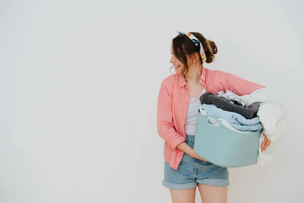 Young happy woman with laundry basin full of washed towels — Stock Photo, Image