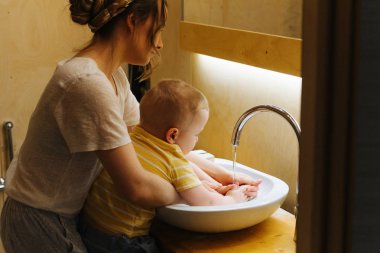 Mutlu anne ve oğlu banyo lavaboellerini yıkayın