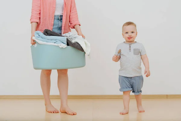 布でいっぱいの洗濯洗面器を持つ母親とジャムで口汚れた彼女の子供 — ストック写真
