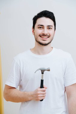 Elinde demir çekiçle evde orta yaşlı bir adamın portresi