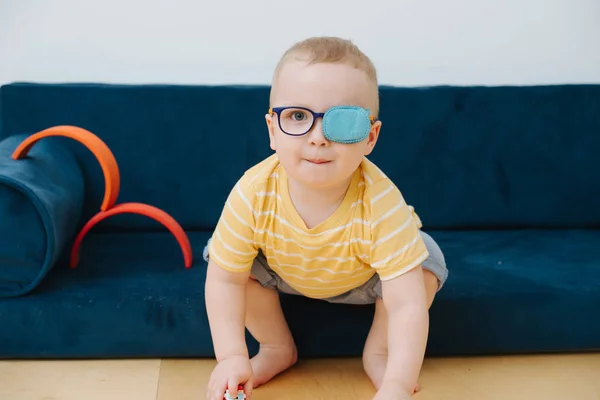 Little toddler boy in lazy eye patch is playing with toy cars — Stock Photo, Image