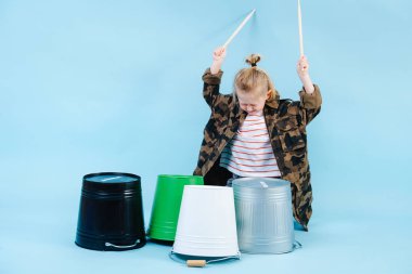 Küçük çocuk demir ve plastik kovalarda baget kullanıyor. Ritim çalma.