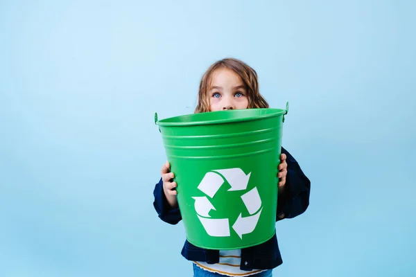Little Girl patrząc na zielone recicle bin. Trzymanie w rękach. — Zdjęcie stockowe