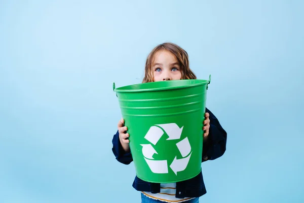 Niña mirando por encima de la papelera recicle verde. Sostenerse en las manos . — Foto de Stock