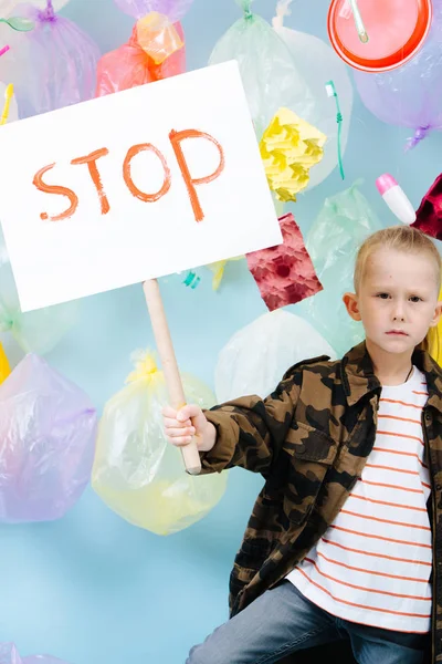 Little boy holding stop sign in protest against pollution and waste crisis