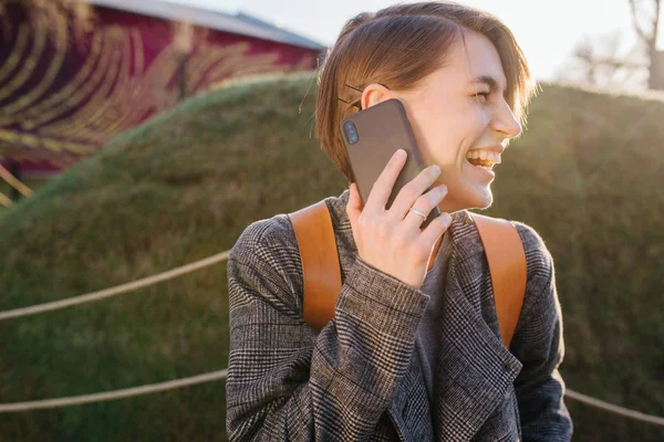 Jong gelukkig aantrekkelijk kortharig brunette vrouw met telefoon in een park — Stockfoto
