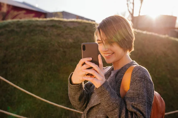 Fiatal boldog vonzó rövid hajú barna nő telefonnal a parkban — Stock Fotó