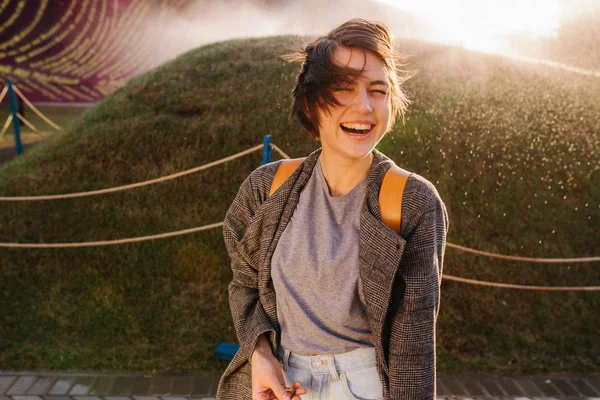 Young laughing woman sprayed by automatic irrigation — Stock Photo, Image