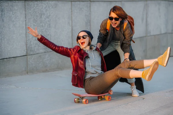 Twee jonge vriendinnen die samen plezier hebben met skateboard — Stockfoto