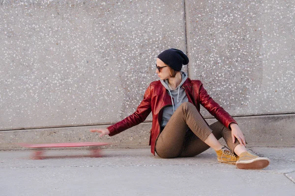 Jovem feliz luz morena mulher sentada com skate em um chão de rua — Fotografia de Stock