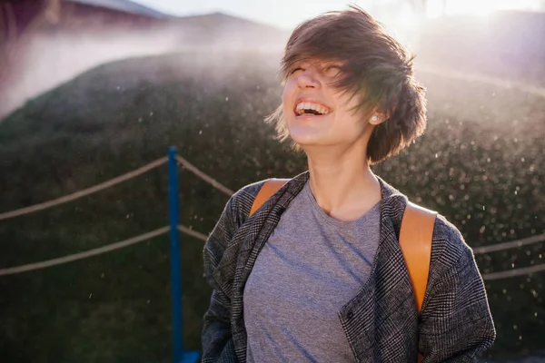 Young laughing woman sprayed by automatic irrigation — Stock Photo, Image