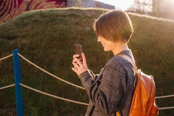 Jong gelukkig aantrekkelijk kortharig brunette vrouw met telefoon in een park — Stockfoto