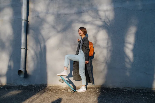 Jovem feliz morena de cabelos curtos está dando um passeio com patins em uma cidade . — Fotografia de Stock
