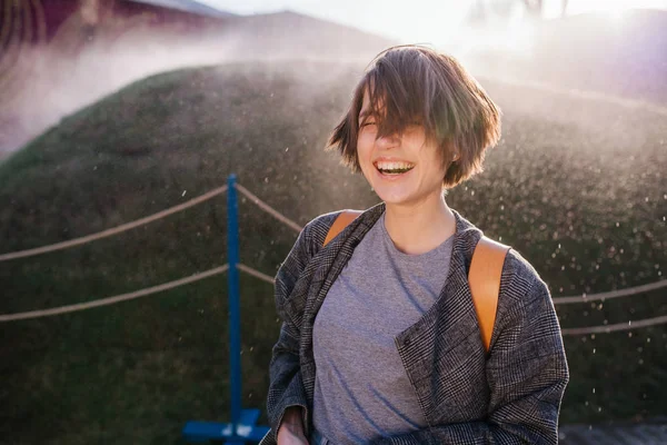Young laughing woman sprayed by automatic irrigation — Stock Photo, Image
