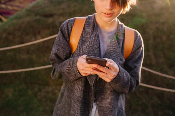 Jong aantrekkelijke kortharige brunette vrouw met telefoon in een park — Stockfoto