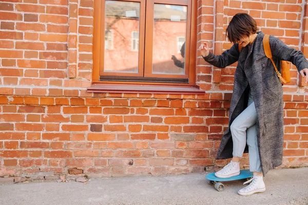 Mladá žena kráčí po ulici a drží skateboard. fotografie životního stylu. — Stock fotografie