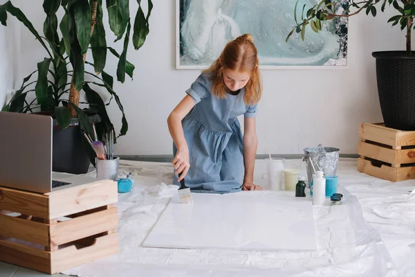 십대 빨간 머리 소녀는 작업장에서 바닥에 큰 캔버스에 브러시로 그림. — 스톡 사진