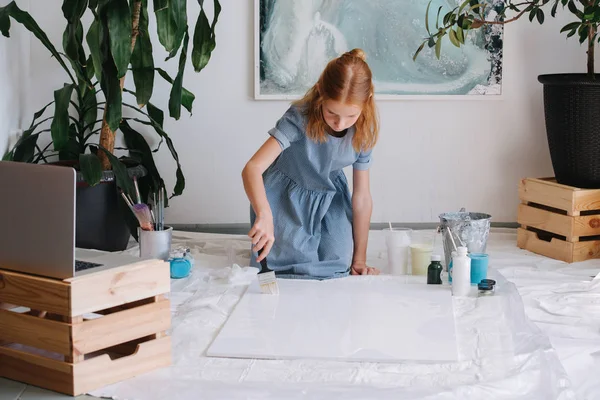 Adolescenta roscata fata este pictura cu perie pe panza mare pe podea într-un atelier . — Fotografie, imagine de stoc