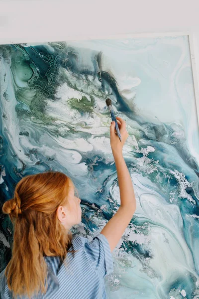 Девочка-подросток рисует на холсте, висящем на стене. . — стоковое фото