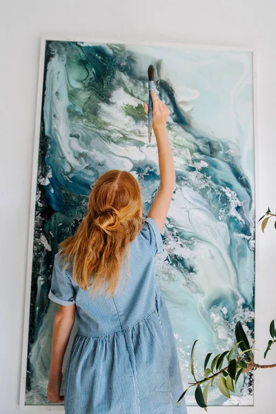 Adolescente ruiva menina está pintando em uma tela pendurada na parede . — Fotografia de Stock