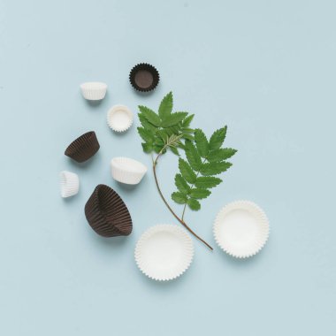 Mavi yüzeyde yatan fincan kek ve rowan dalı için sarma kağıtları