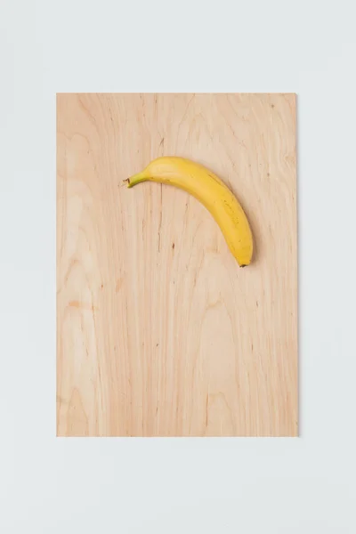 Cutting board with banana on it over white background — Stock Photo, Image