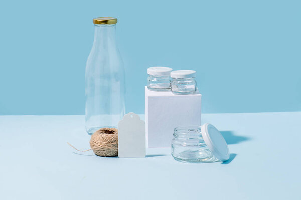 Glass bottle and jars with hank of twine over blue background.