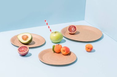 Mavi üzerine kompostlanabilir kağıt tabaklar üzerinde meyve kompozisyonu