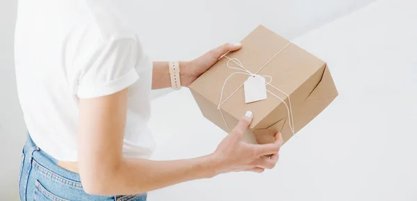 Woman in casual clothes holding postal cardboard box, checking wrappings at home