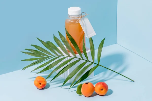Composition of peach juice on pedestal, fresh apricots and palm branch