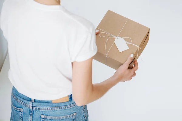 Woman in casual clothes holding postal cardboard box, checking wrappings at home