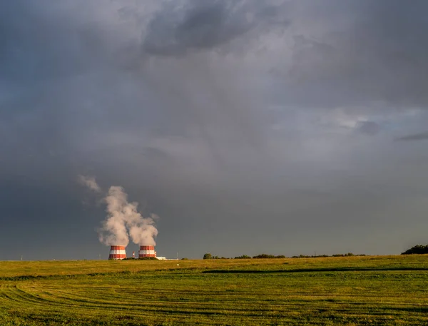 Biçilmiş alan, gri bulutlu gökyüzü ve ufuk üzerinde buharlı soğutma kuleleri — Stok fotoğraf