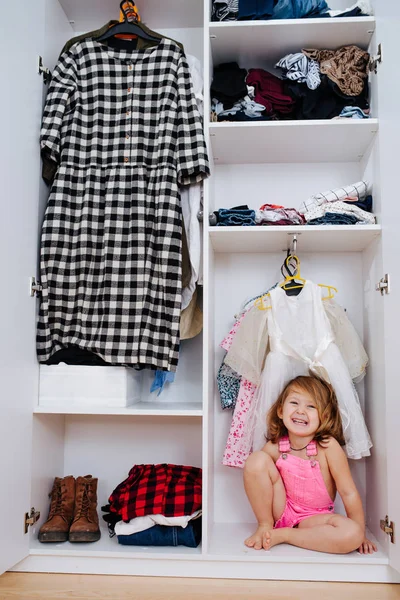 Πορτρέτο του μικρού κοριτσιού σε νέες ροζ φόρμες που κάθονται μέσα από ανοιχτή ντουλάπα — Φωτογραφία Αρχείου