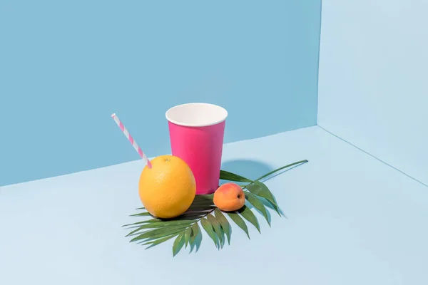 Palmiye dalı üzerinde saman ile kağıt bardak, taze şeftali ve portakal Kompozisyon — Stok fotoğraf