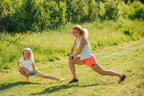 Familie doet fysieke oefeningen buiten, stretching, stretching heupen. — Stockfoto