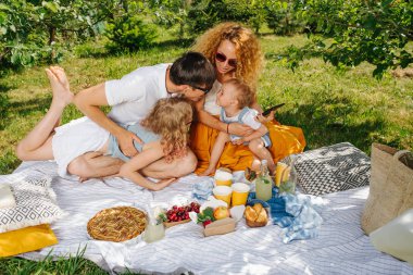 Ağaçların nazik gölgesi altında bahçelerde çim üzerinde aile piknik