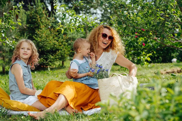 Ağaçların nazik gölgesi altında bahçelerde çim üzerinde aile piknik