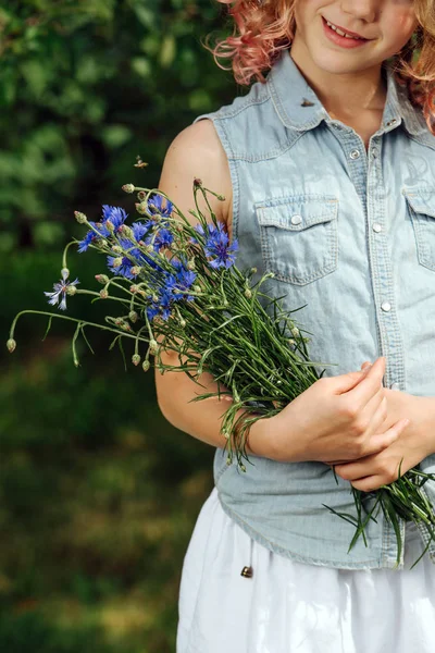 Tonårs flicka med lockigt hår håller blå bukett av ängsblommor — Stockfoto