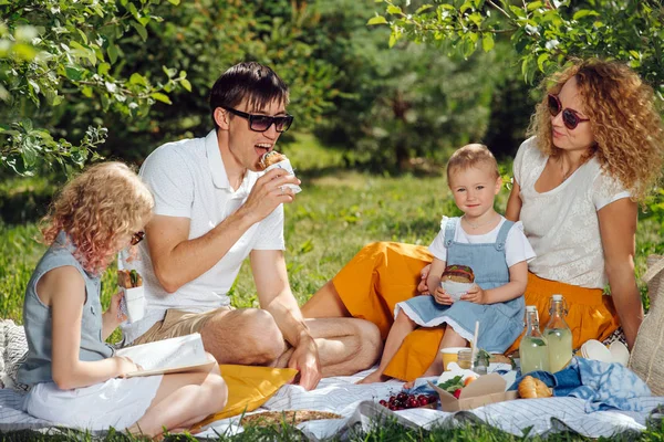 Family picnic on grass in the gardens under gentle shade of trees — Stock Photo, Image