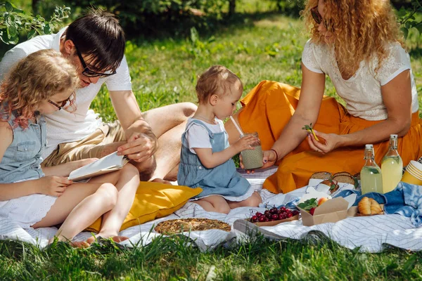 Ağaçların nazik gölgesi altında bahçelerde çim üzerinde aile piknik — Stok fotoğraf