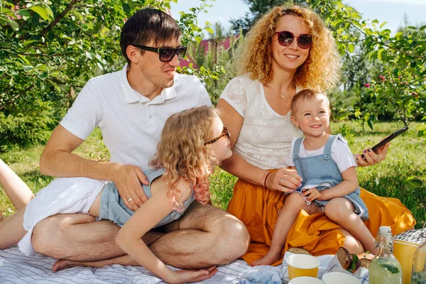 Ağaçların nazik gölgesi altında bahçelerde çim üzerinde aile piknik — Stok fotoğraf