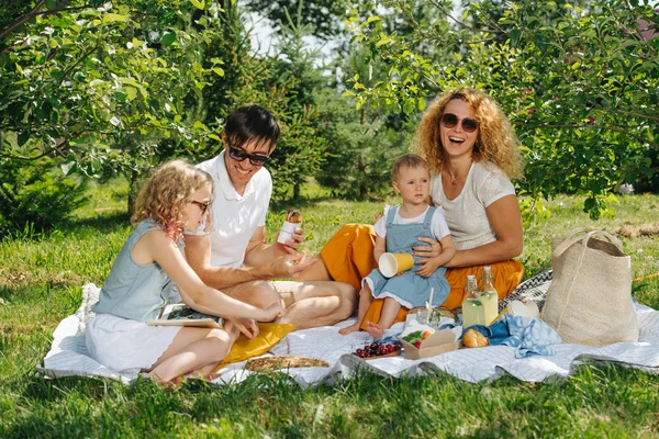 Ağaçların nazik gölgesi altında bahçelerde çim üzerinde aile piknik — Stok fotoğraf