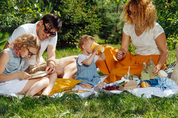 Ağaçların nazik gölgesi altında bahçelerde çim üzerinde aile piknik — Stok fotoğraf