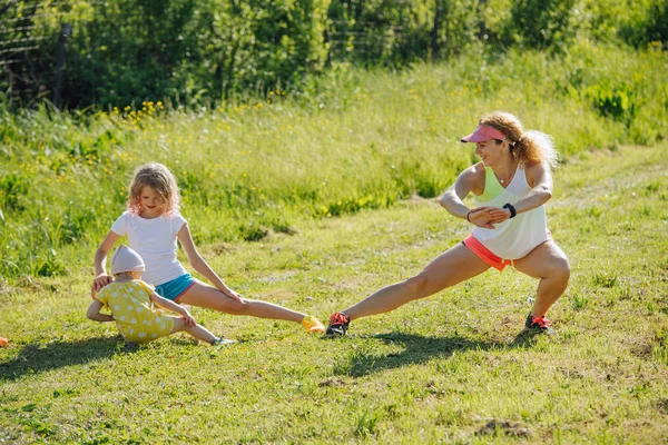 La familia está haciendo ejercicios físicos al aire libre, estiramiento, embestida lateral . — Foto de Stock