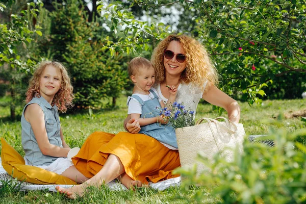Ağaçların nazik gölgesi altında bahçelerde çim üzerinde aile piknik
