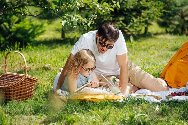 Genç kız aile piknik sırasında çim üzerinde babası ile kitap okuma — Stok fotoğraf