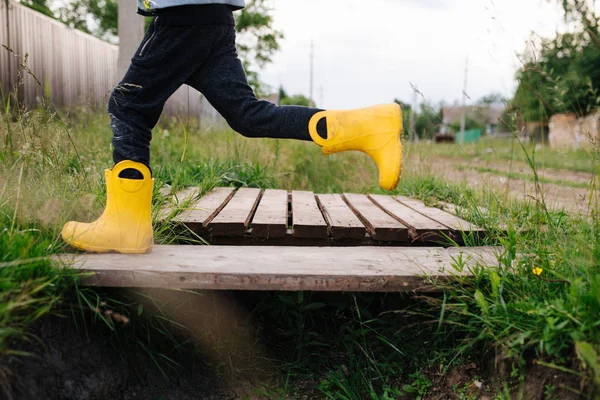 Muy feliz niño está corriendo rápido en botas de goma amarillas —  Fotos de Stock