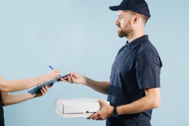 Bir kuryeden kutu teslimatını kabul eden kadın eli, kalemle kağıt formu imzalama
