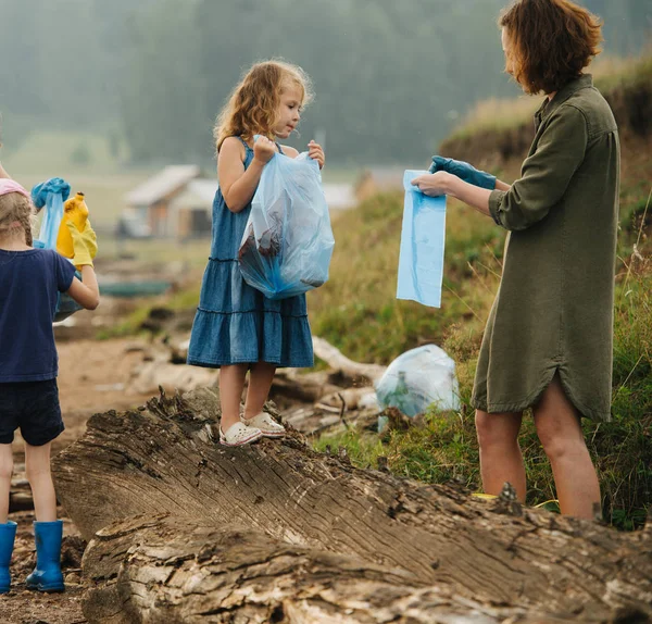 Nehir kıyısında çöp toplayan bir grup çocuklu kadın — Stok fotoğraf