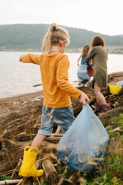 Familie sammelt an einem trüben Sommertag Müll am Flussufer — Stockfoto